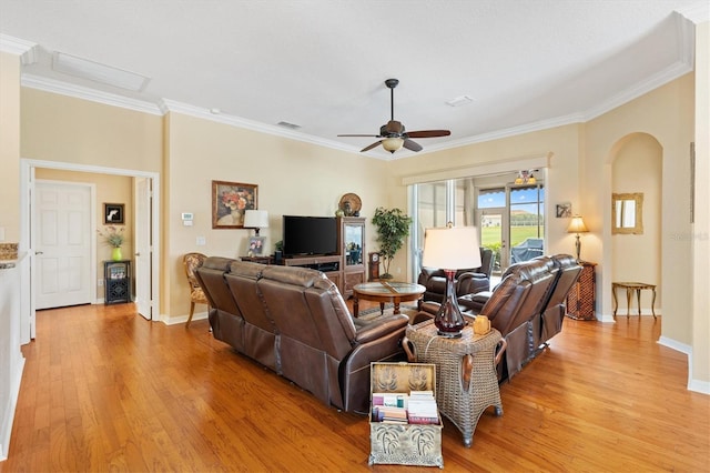 living room with arched walkways, light wood-style floors, ornamental molding, a ceiling fan, and baseboards