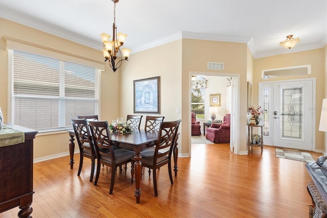 dining room with a chandelier, healthy amount of natural light, crown molding, light wood-style flooring, and baseboards