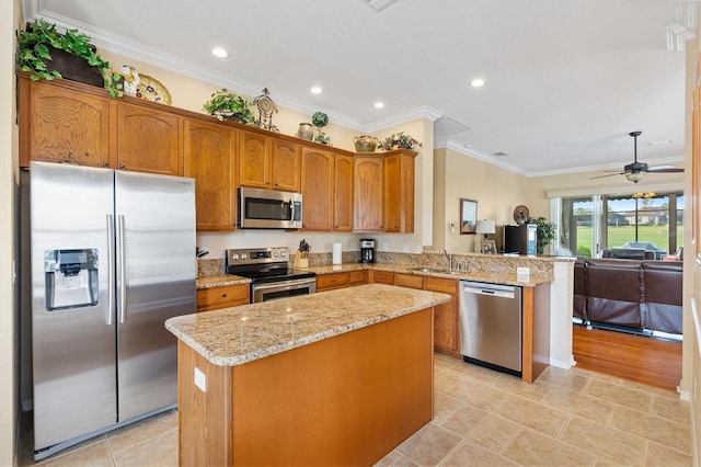 kitchen featuring stainless steel appliances, a sink, a peninsula, a center island, and crown molding
