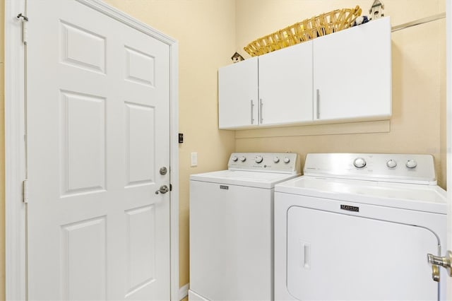 clothes washing area with independent washer and dryer and cabinet space