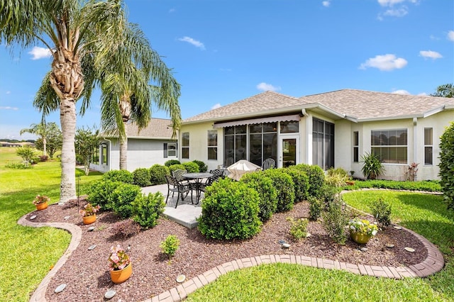 rear view of property with stucco siding, a yard, a patio area, a sunroom, and roof with shingles