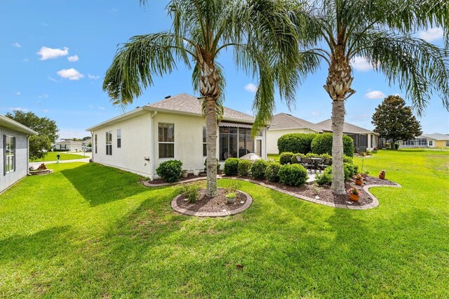 view of front of house with a front yard, stucco siding, a sunroom, and a patio
