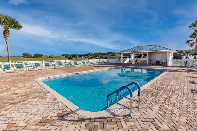 community pool featuring fence and a patio