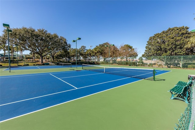 view of tennis court with community basketball court and fence