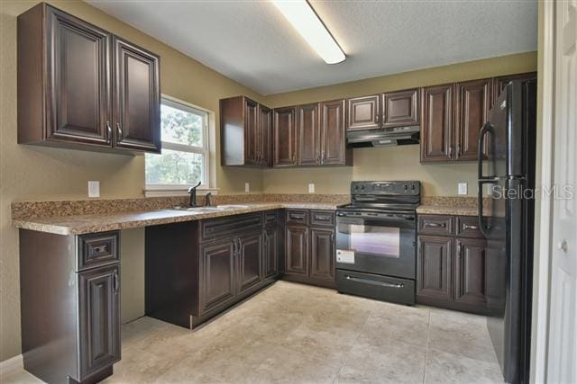kitchen featuring under cabinet range hood, dark brown cabinets, a sink, black appliances, and light countertops