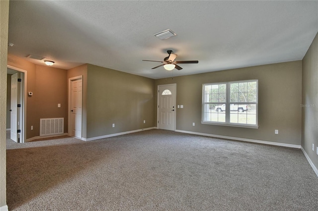 carpeted spare room with baseboards, ceiling fan, and visible vents