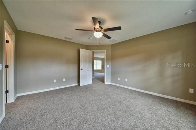 carpeted spare room with baseboards, a ceiling fan, and visible vents