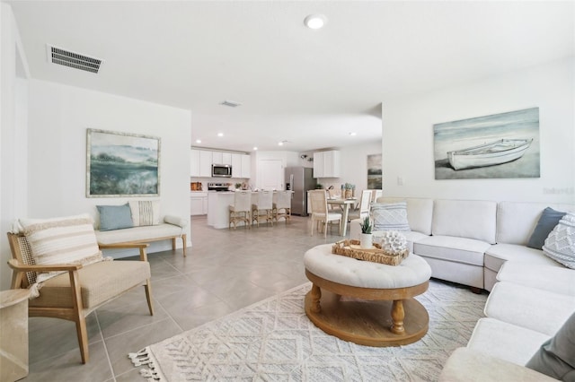 living area with light tile patterned floors, visible vents, and recessed lighting