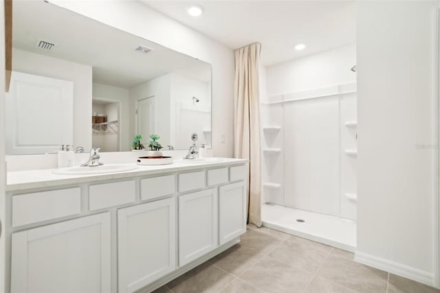 full bath with a sink, visible vents, tile patterned floors, a shower stall, and double vanity