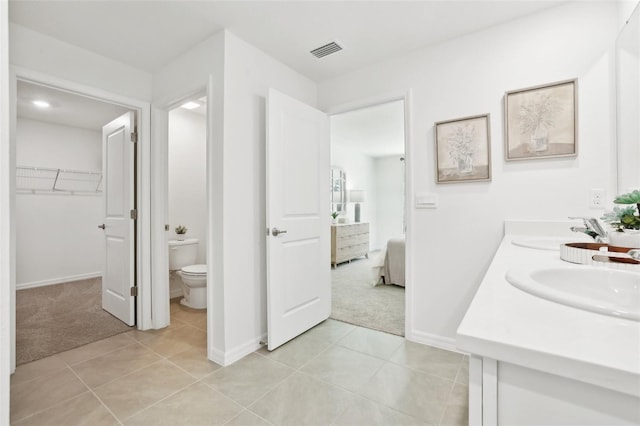 ensuite bathroom featuring toilet, baseboards, visible vents, a sink, and tile patterned floors