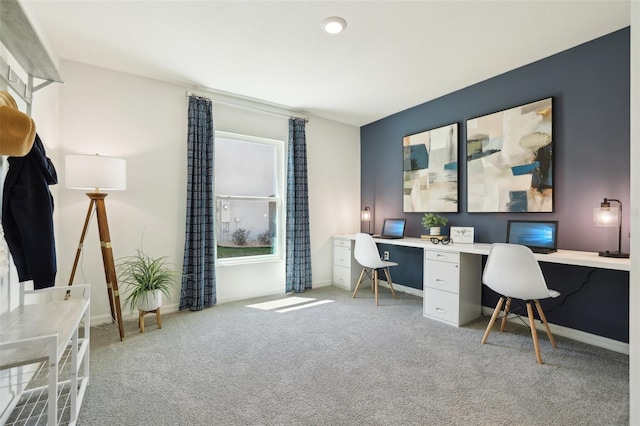 carpeted office featuring built in desk and baseboards