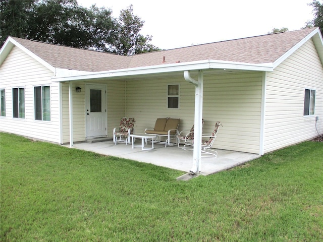 back of property with a yard, a shingled roof, and a patio