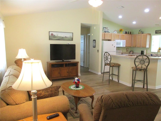 living area featuring lofted ceiling, baseboards, light wood-type flooring, and recessed lighting