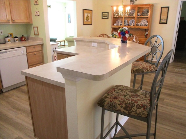 kitchen featuring a breakfast bar, light countertops, white dishwasher, and wood finished floors