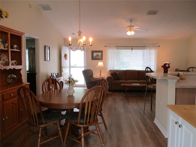 dining area featuring plenty of natural light, ceiling fan with notable chandelier, dark wood-type flooring, and visible vents