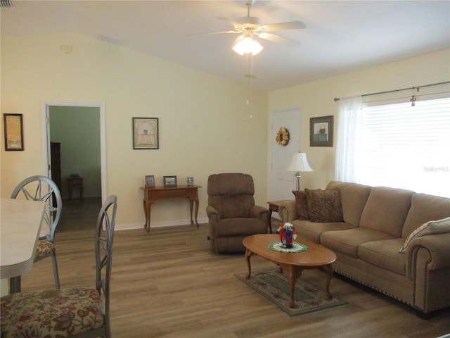 living area featuring a ceiling fan, baseboards, light wood-style flooring, and vaulted ceiling