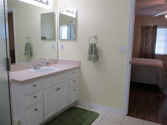 ensuite bathroom featuring a ceiling fan, tile patterned floors, baseboards, ensuite bath, and vanity