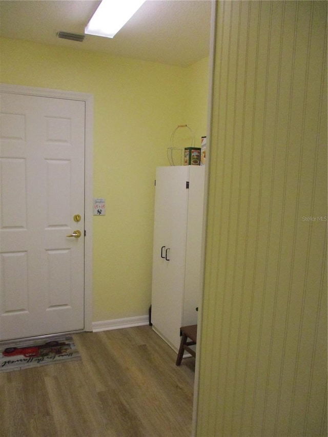 laundry room with baseboards, visible vents, and wood finished floors