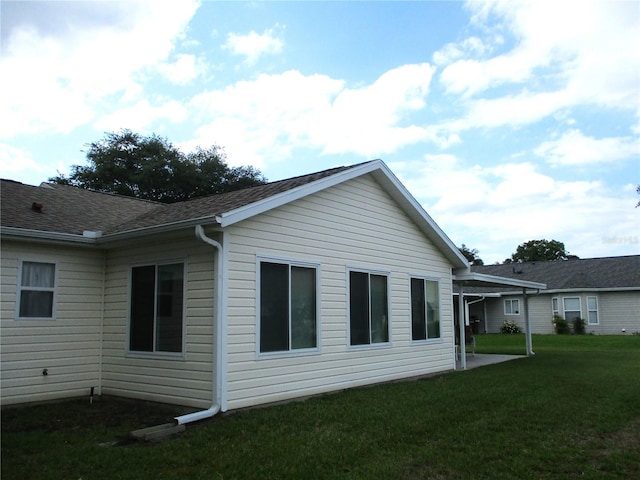view of side of home featuring a lawn and roof with shingles
