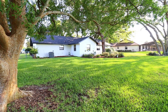 5351 SW 80th Pl, Ocala, FL 34476 - back of house featuring cooling unit, a yard, stucco siding, and a shingled roof