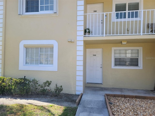 entrance to property with stucco siding and a balcony