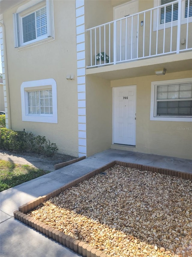property entrance with a balcony and stucco siding