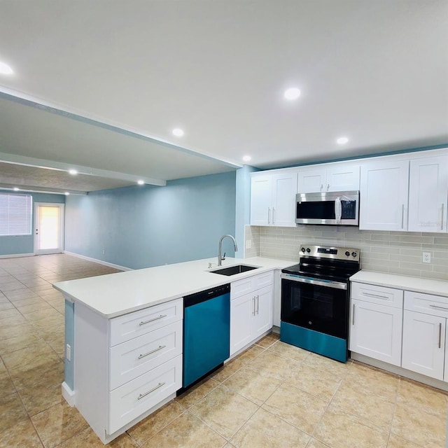 kitchen featuring appliances with stainless steel finishes, a sink, a peninsula, backsplash, and light countertops