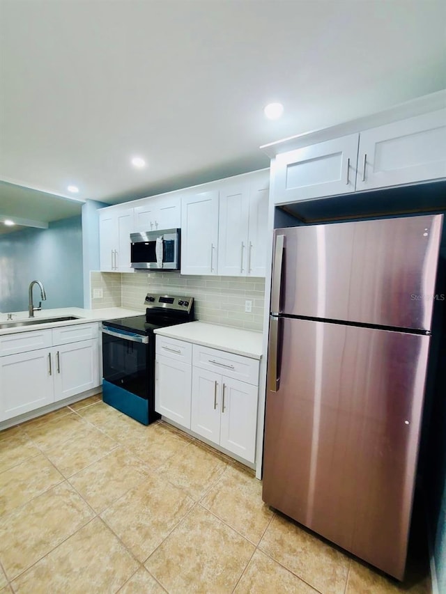 kitchen featuring appliances with stainless steel finishes, a sink, decorative backsplash, light countertops, and white cabinets