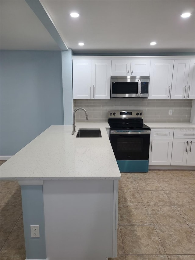 kitchen featuring appliances with stainless steel finishes, a sink, tasteful backsplash, white cabinetry, and recessed lighting