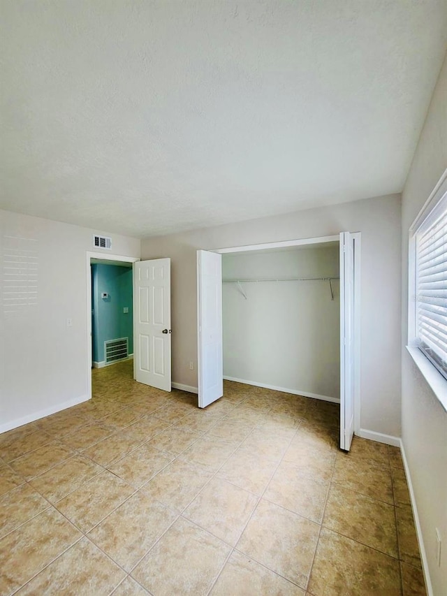 unfurnished bedroom featuring a closet, light tile patterned floors, and baseboards