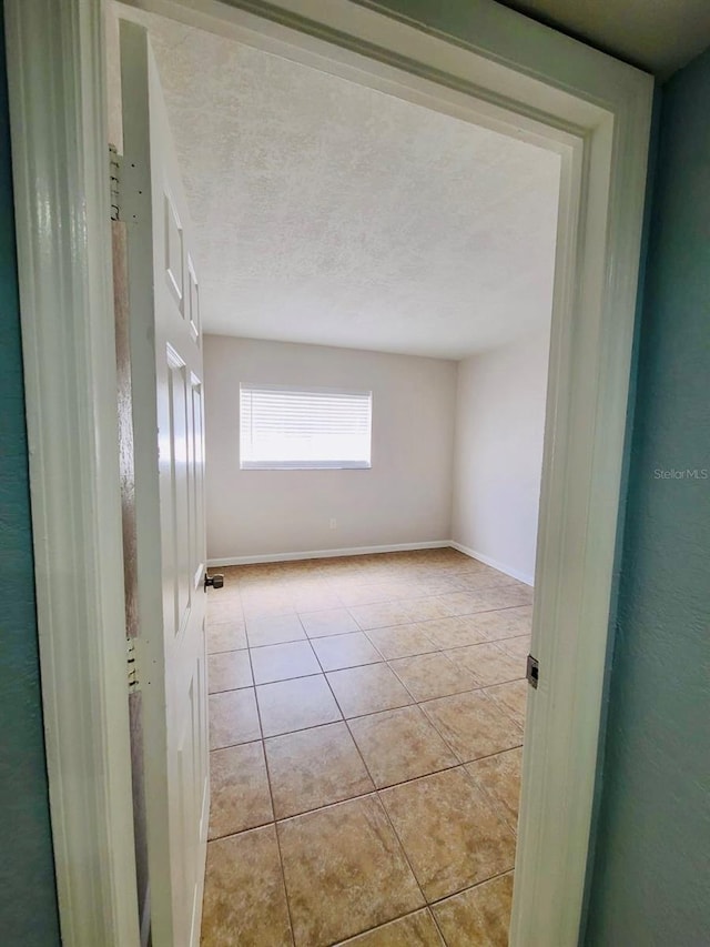 spare room with light tile patterned flooring and baseboards