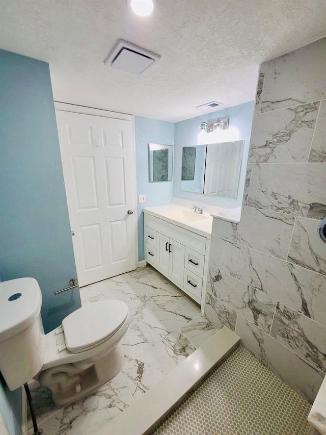 bathroom featuring toilet, marble finish floors, vanity, and a textured ceiling