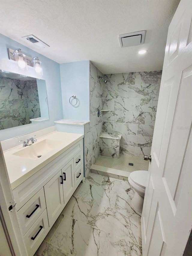 bathroom featuring toilet, vanity, a tile shower, marble finish floors, and recessed lighting