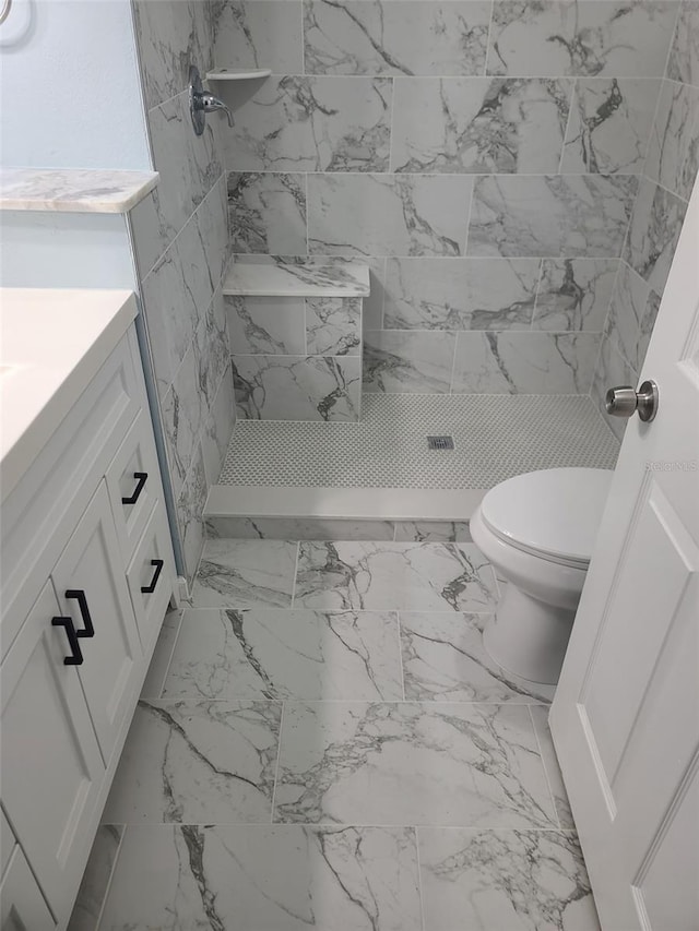 bathroom featuring toilet, vanity, a stall shower, and marble look tile flooring