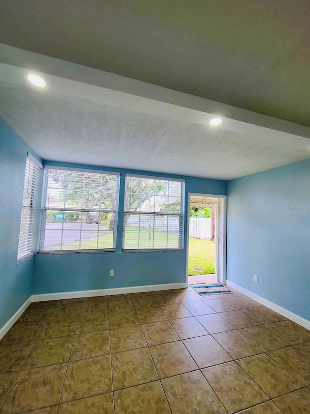 tiled spare room featuring recessed lighting, baseboards, and a textured ceiling