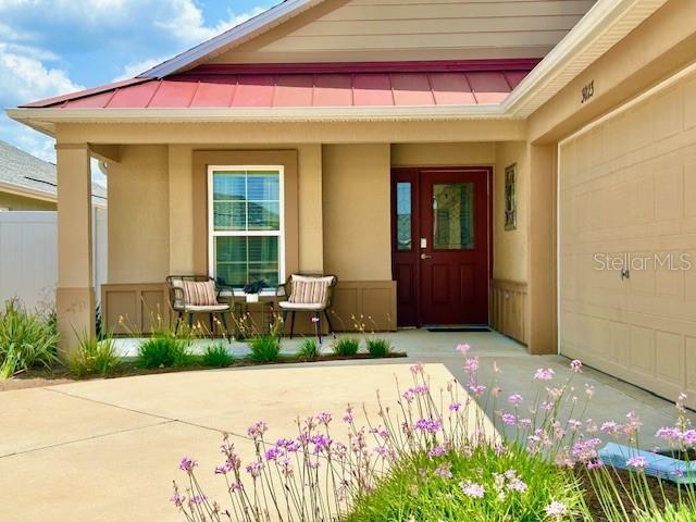 3023 Charlevoix St, The Villages, FL 32163 - doorway to property featuring covered porch, stucco siding, and driveway
