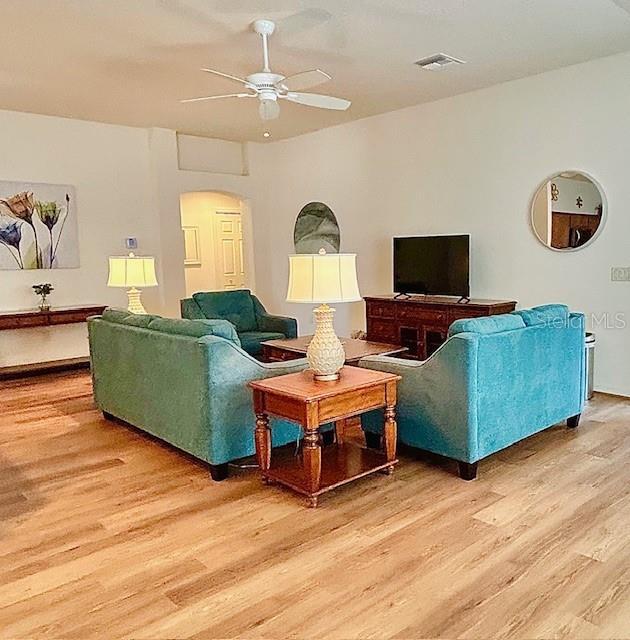3023 Charlevoix St, The Villages, FL 32163 - living area featuring light wood-style floors, arched walkways, and a ceiling fan