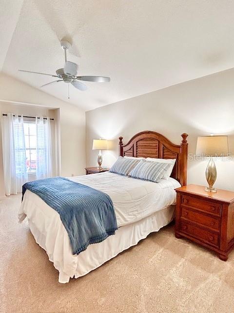 3023 Charlevoix St, The Villages, FL 32163 - bedroom featuring light carpet, lofted ceiling, and ceiling fan
