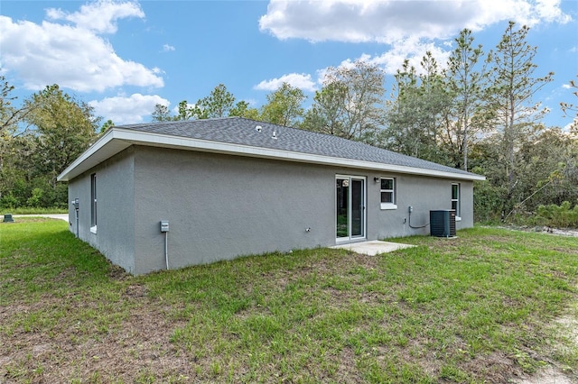 23163 NW Shamrock Ave, Dunnellon, FL 34431 - back of property with stucco siding, a lawn, a shingled roof, and central AC