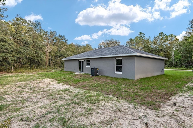 23163 NW Shamrock Ave, Dunnellon, FL 34431 - back of house with central air condition unit, stucco siding, and a lawn