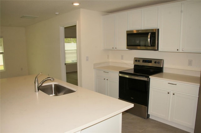 kitchen with appliances with stainless steel finishes, a sink, white cabinets, light countertops, and recessed lighting