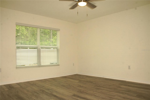 empty room with ceiling fan, dark wood finished floors, and baseboards