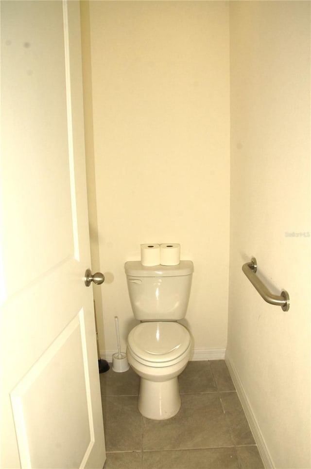 bathroom with toilet, baseboards, and tile patterned floors