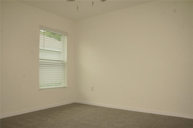 empty room with carpet floors, a ceiling fan, and baseboards