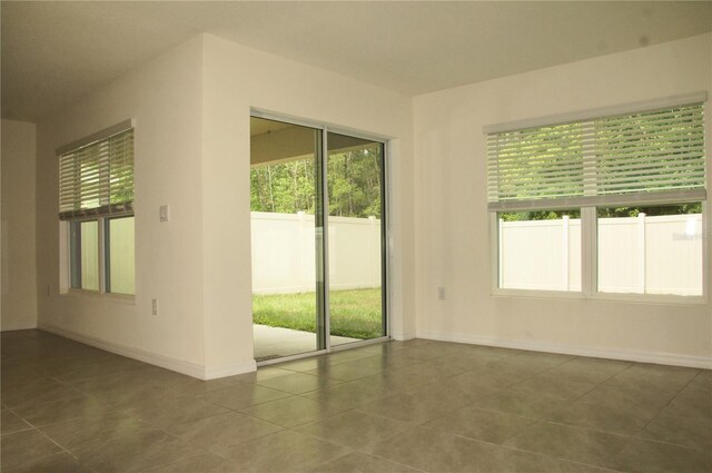 tiled spare room with plenty of natural light and baseboards