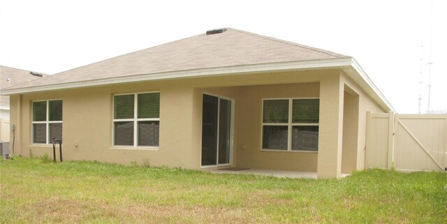 rear view of property with stucco siding, a gate, and a patio area