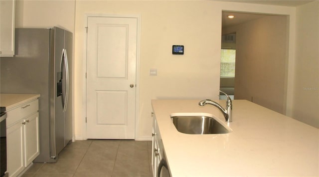 kitchen featuring a sink, stainless steel refrigerator with ice dispenser, tile patterned flooring, light countertops, and white cabinets