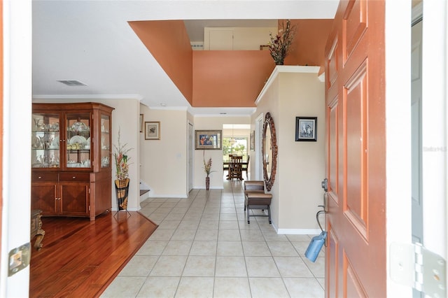 entryway featuring baseboards, ornamental molding, light tile patterned floors, and a towering ceiling
