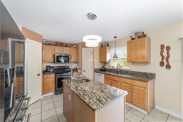 kitchen with stainless steel appliances, a sink, a center island with sink, and decorative light fixtures