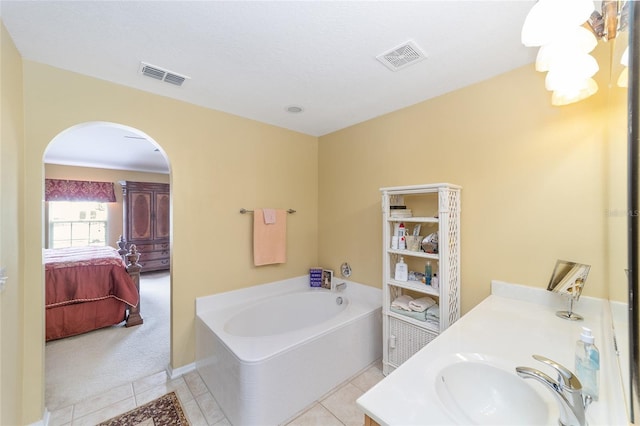 ensuite bathroom with tile patterned flooring, a garden tub, and vanity